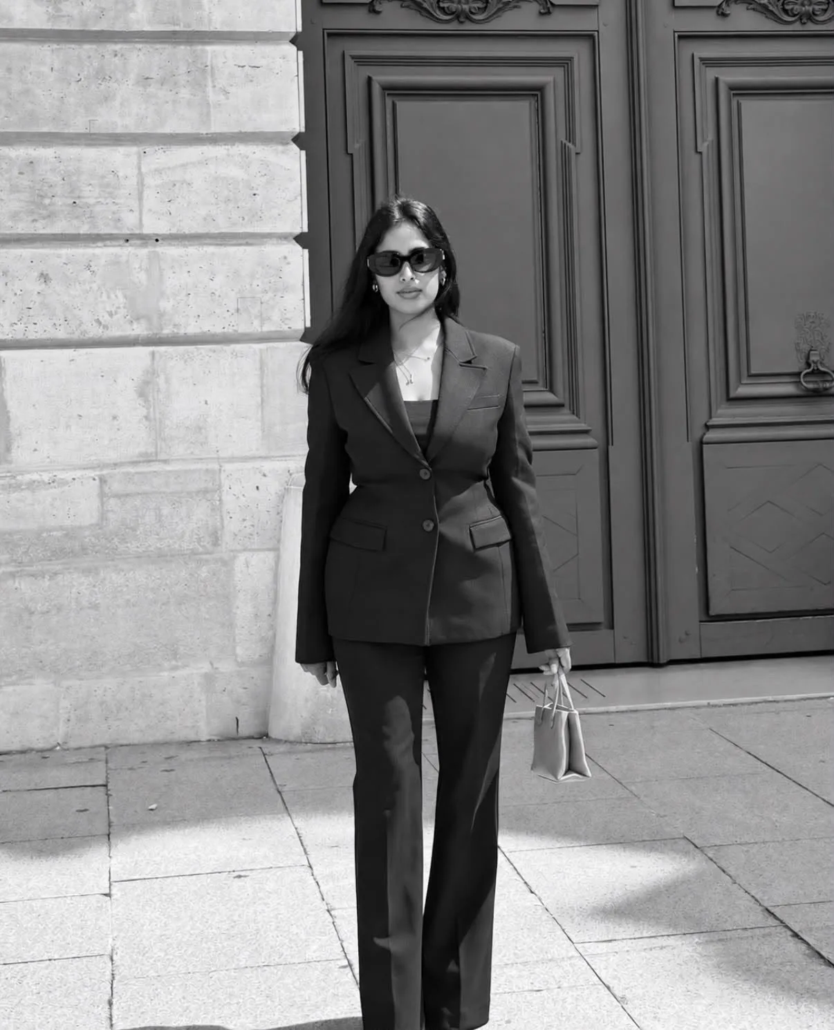 Giraldine SANTO, fondatrice d’EAST EDIT, en tailleur noir devant une porte parisienne